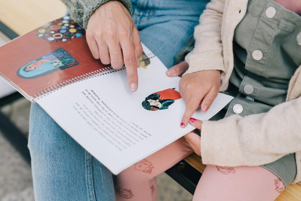 A mother and child enjoy reading a Braille storybook together outdoors, fostering bonding and learning.